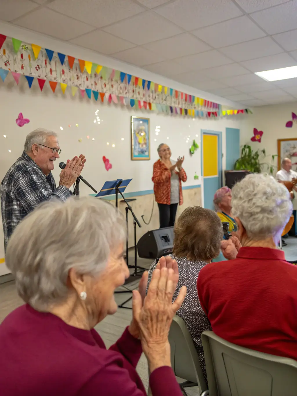 A vibrant photograph capturing a Y'AKAOUIR musical performance in a local community center, showcasing musicians and clowns interacting with an enthusiastic audience of all ages.